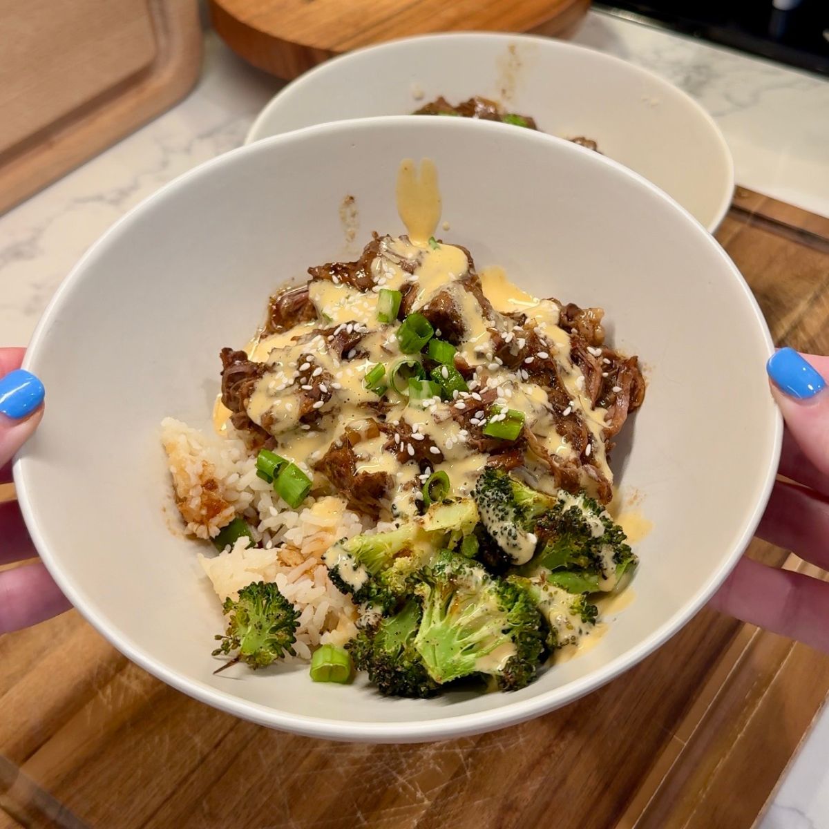 crockpot korean beef bowls with sauce on top, broccoli and rice