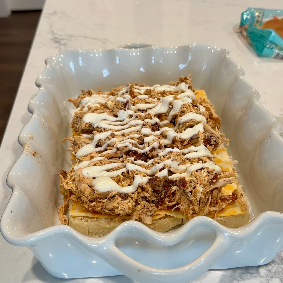 ranch dressing on chicken mixture on bread in baking tray
