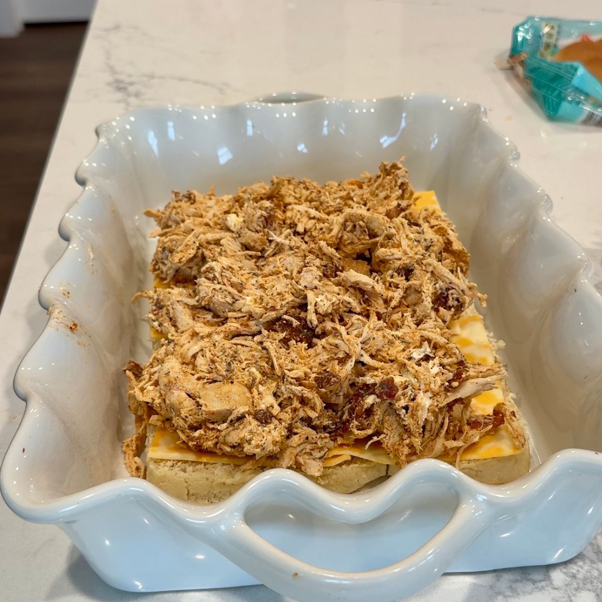 chicken on top of cheese on bread in baking tray