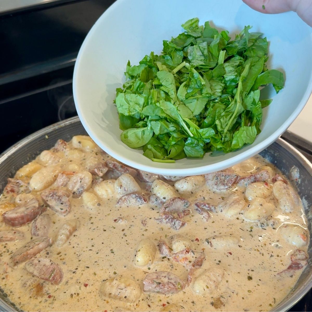 spinach in bowl over creamy sauce in skillet