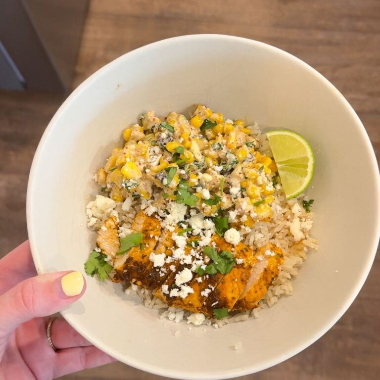 chicken street corn bowl in cream bowl with hand holding it