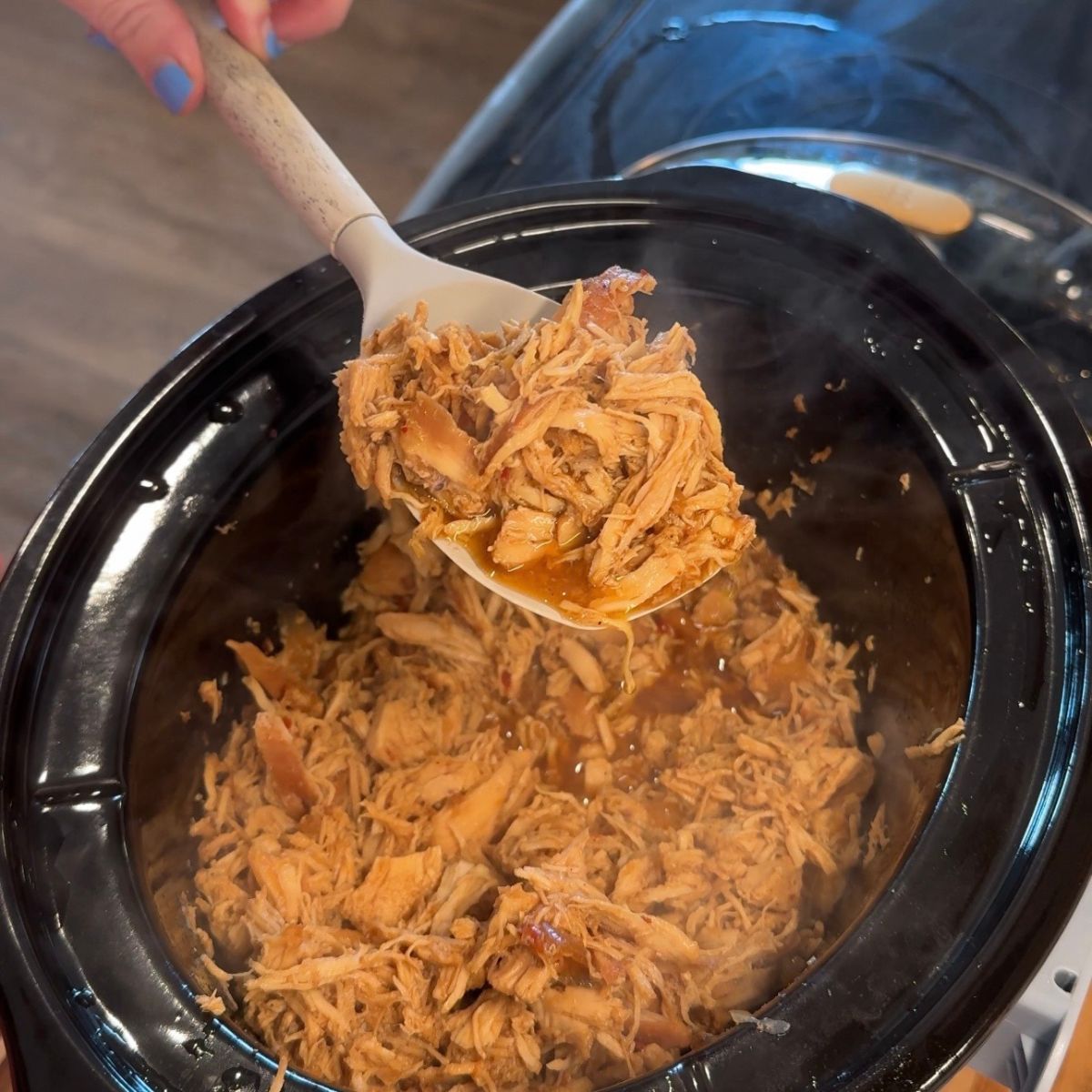 chicken on spoon over slow cooker