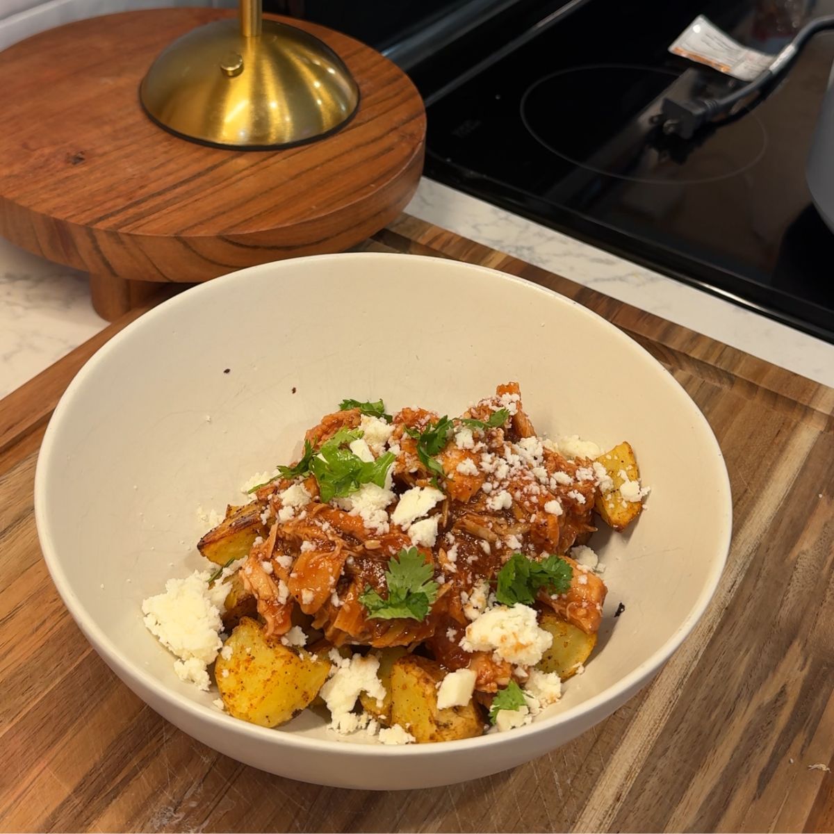 honey chipotle bbq chicken in bowl with diced potatoes, cheese and cilantro