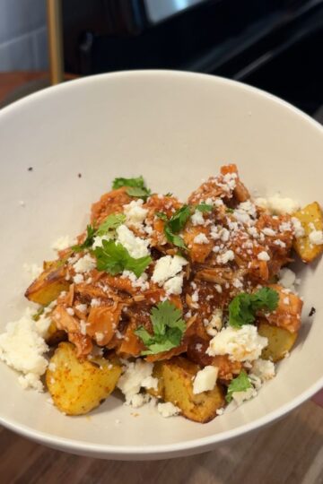 crockpot honey chipotle bbq chicken in bowl with cheese and cilantro on top