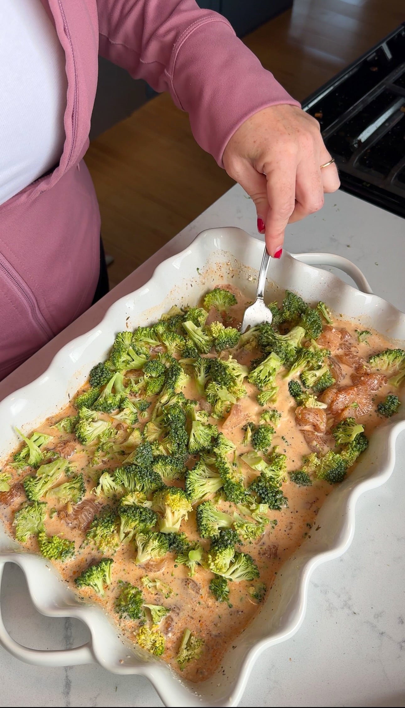 Stirring the ingredients into the seasoned cream sauce with a fork before baking.