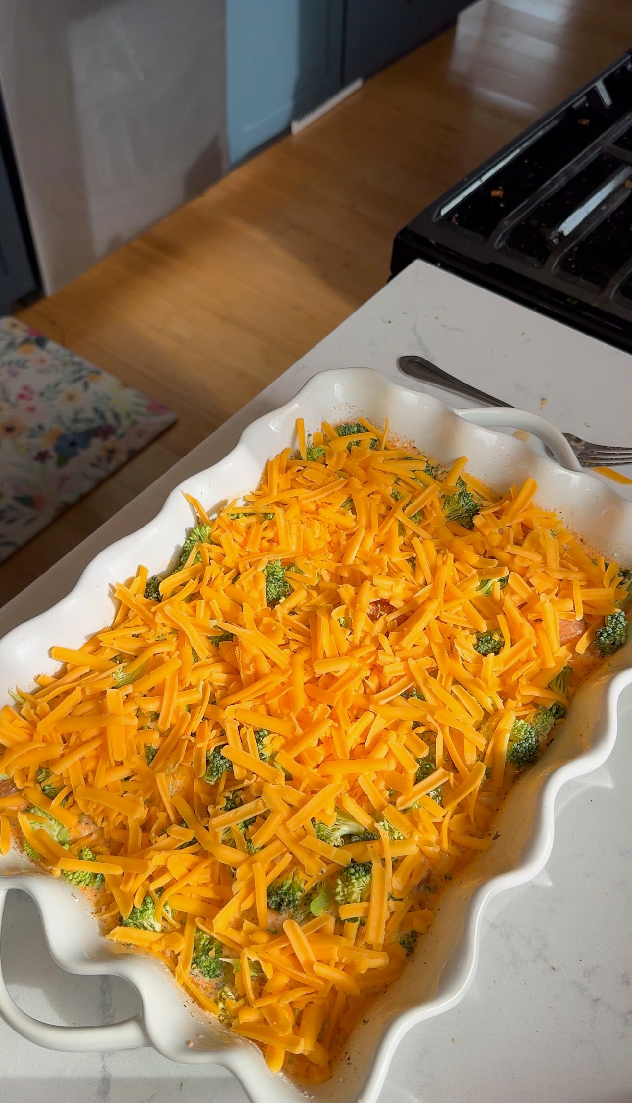 Unbaked chicken and broccoli orzo bake topped with shredded mild cheddar cheese.