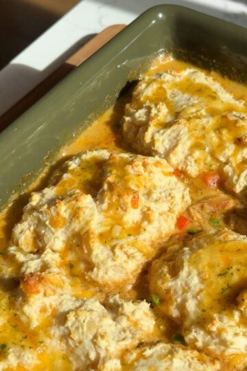 Cheddar bay biscuit chicken pot pie with golden garlic butter biscuits in a green baking dish.