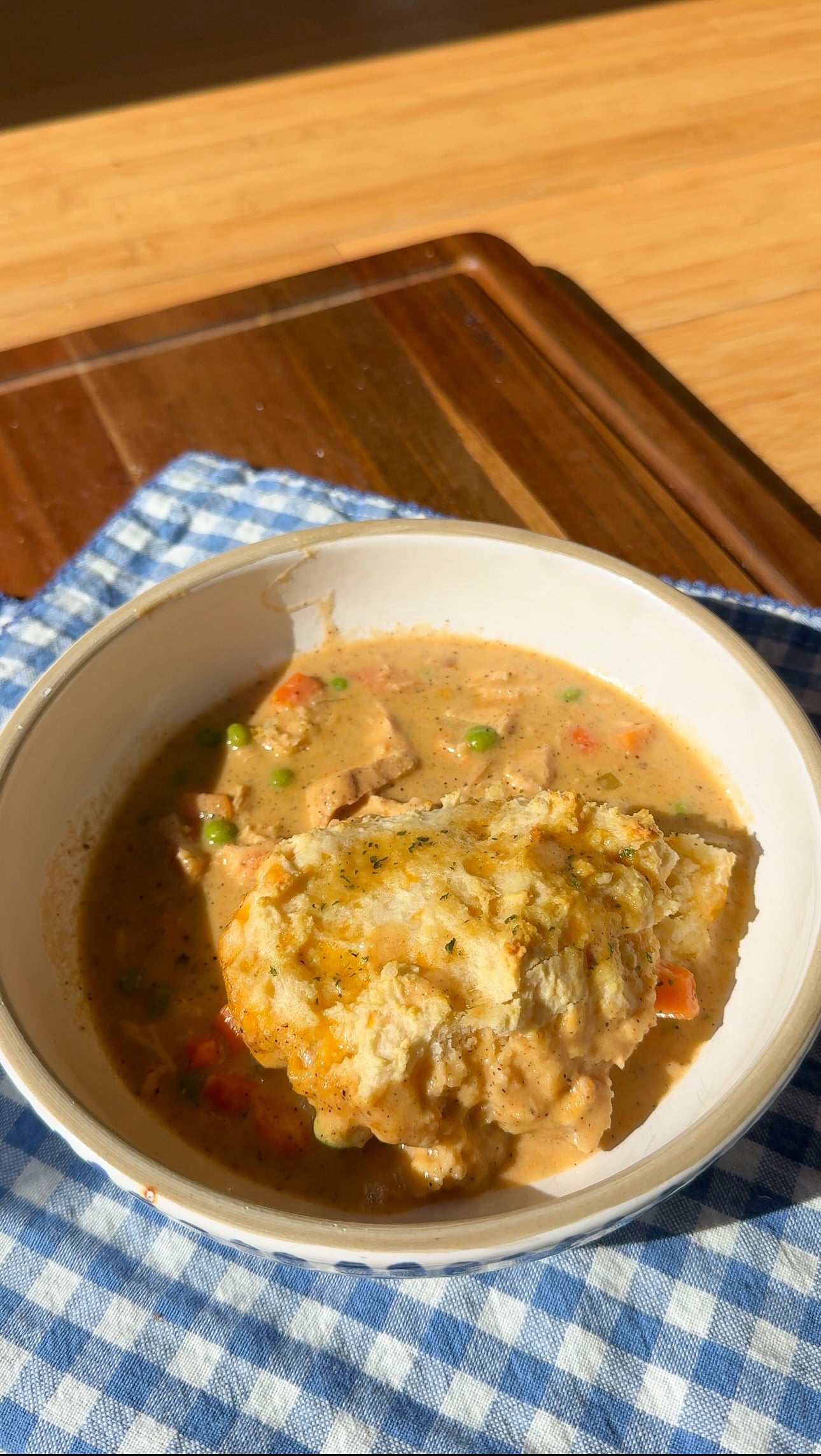 A bowl of creamy cowboy butter chicken pot pie topped with a cheddar biscuit.
