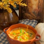 A bowl of crack chicken and dumpling soup topped with shredded cheddar and green onion.
