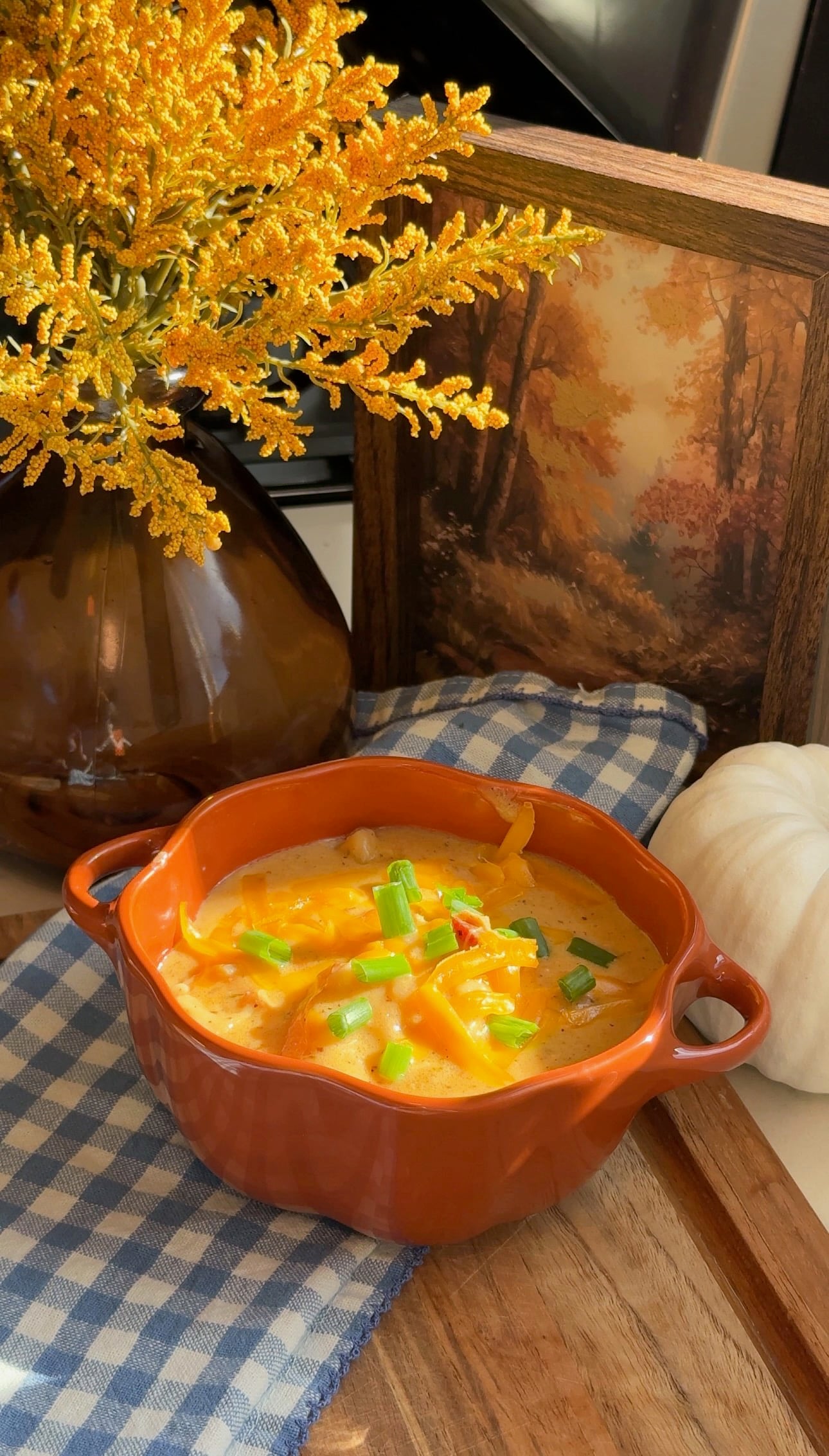 A bowl of crack chicken and dumpling soup topped with shredded cheddar and green onion.