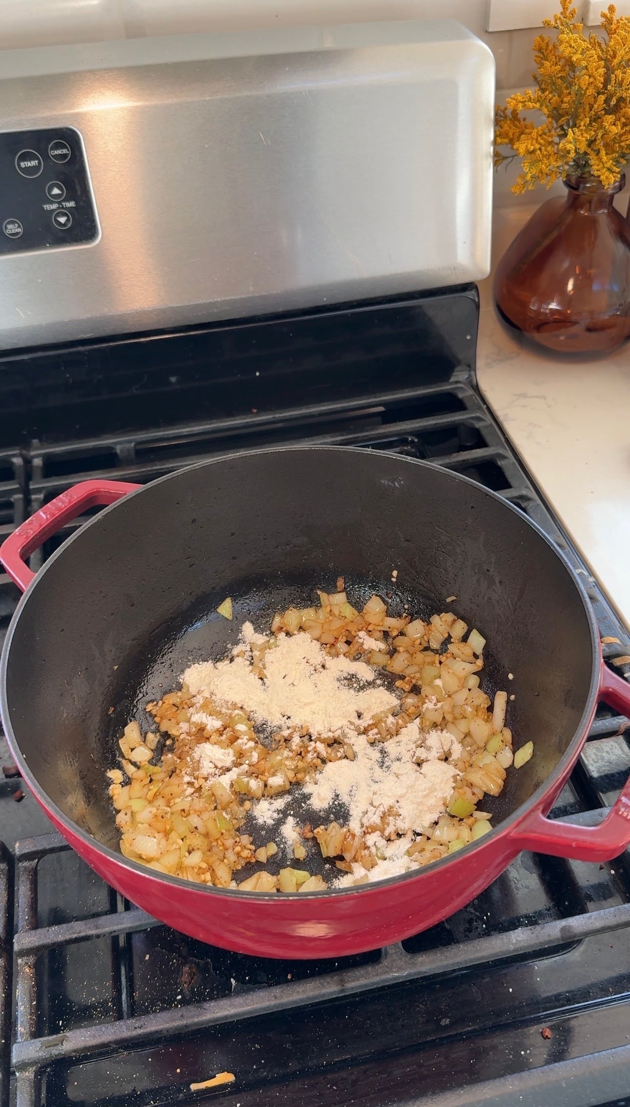 Diced onion cooked in bacon grease and sprinkled with flour in a red Dutch oven.