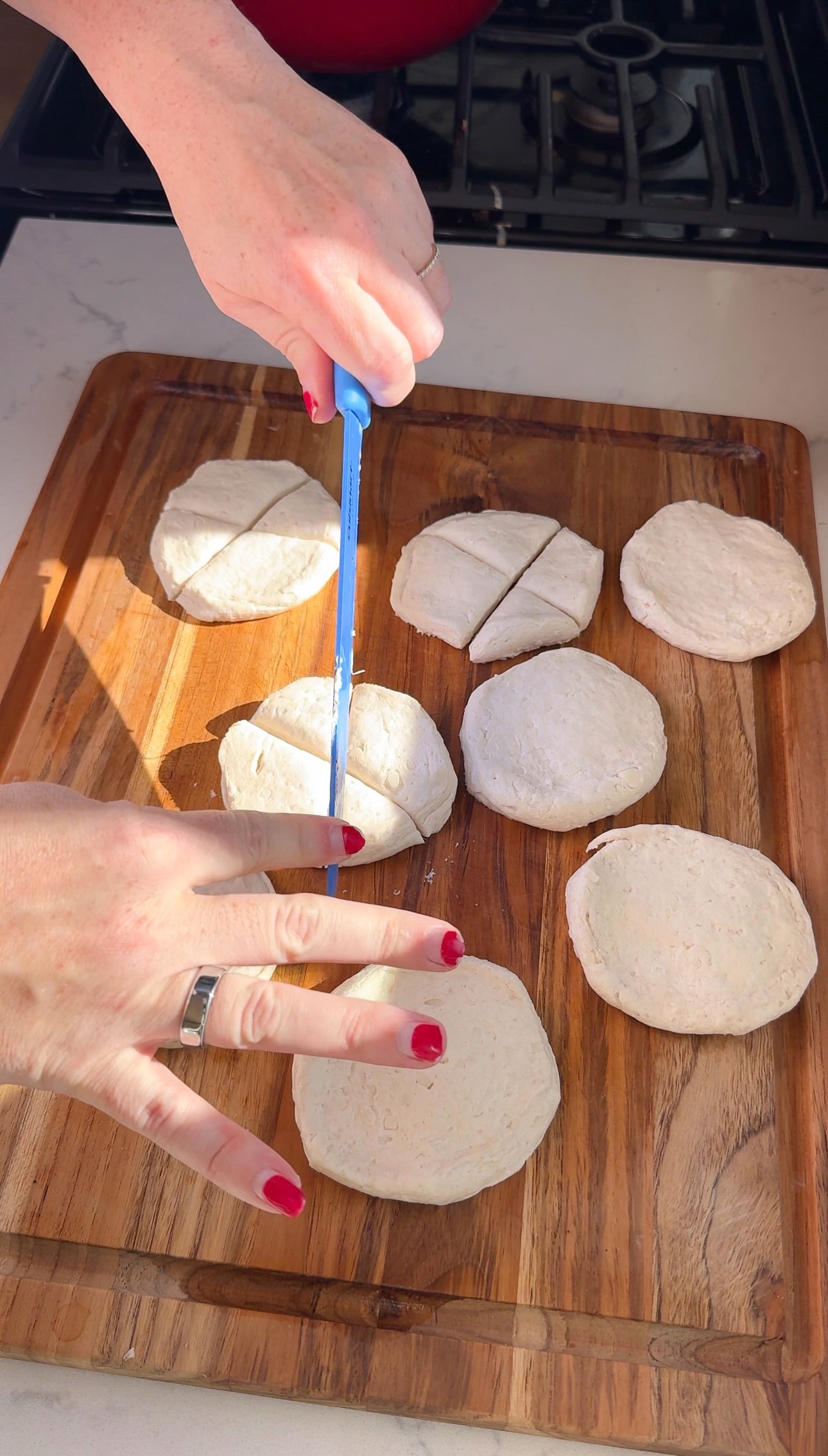 Cutting flattened biscuit dough into quarters with a bench scraper for dumplings.