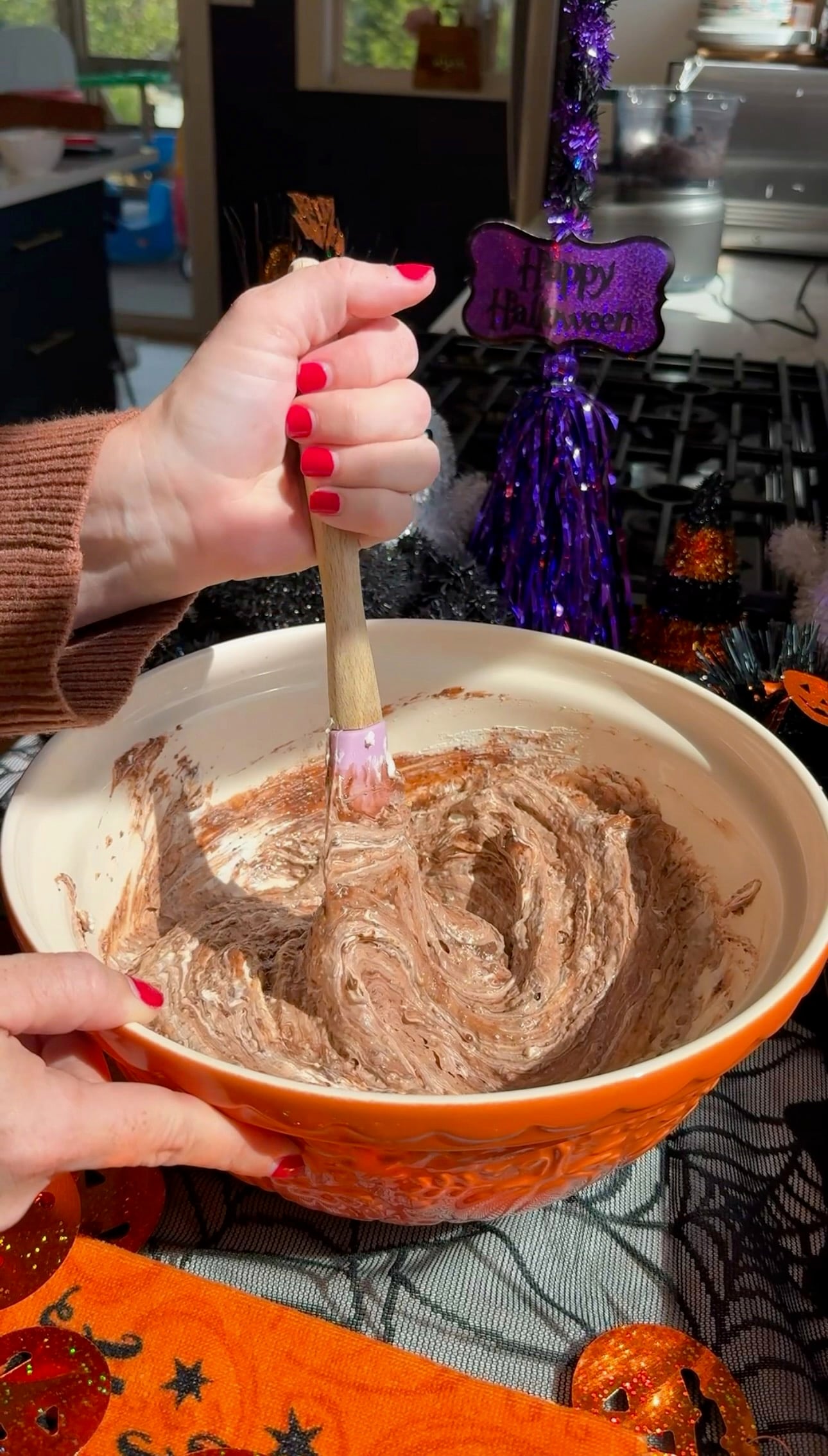 Mixing the creamy chocolate pudding and cream cheese filling in an orange bowl with a spatula.